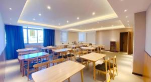 ein Restaurant mit Holztischen und Stühlen und blauen Vorhängen in der Unterkunft Green Tree Inn Jiangsu Changshu Southeast Yuyue Square in Gujiashuigou