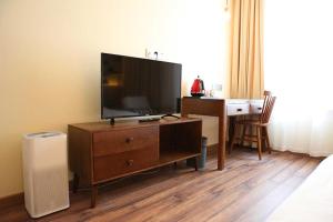 a bedroom with a television on a dresser with a desk at Kaiyue Hotel Qingdao in Qingdao