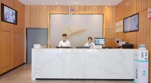 zwei Personen sitzen an einem Tresen in einem Büro in der Unterkunft Green Tree Inn Jiangsu Changshu Southeast Yuyue Square in Gujiashuigou