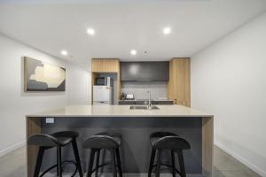 堪培拉Chic Inner-City 2-Bed Abode with Pool Gym & Sauna的厨房配有带凳子的柜台