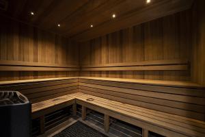 堪培拉Chic Inner-City 2-Bed Abode with Pool Gym & Sauna的一间设有木长椅和垃圾桶的桑拿浴室