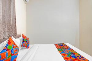 - une chambre avec un lit blanc et des oreillers colorés dans l'établissement FabHotel Platinum - Shivaji Nagar, Commercial Street, à Bangalore
