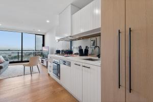 cocina con armarios blancos y vistas al océano en Contemporary 2-Bed Haven with Swimming Pool, en Clayton North