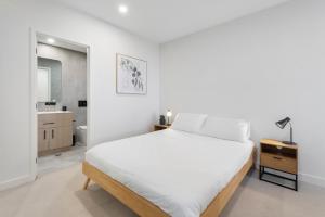 Un dormitorio blanco con una cama y un baño. en Contemporary 2-Bed Haven with Swimming Pool, en Clayton North 6 fotos más