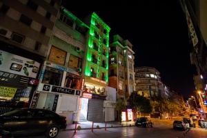 فندق بيستور في إسطنبول: مبنى ذو إضاءة خضراء في شارع المدينة ليلاً