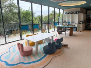 a living room with a table and chairs and windows at Sunshine Layan Beach Resort 2 bedroom #84192 in Layan Beach