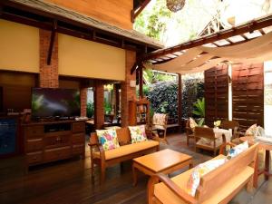 une terrasse avec des canapés, une télévision et une table dans l'établissement Baan Talay Dao Resort, à Hua Hin