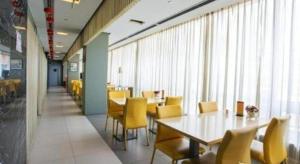 ein Esszimmer mit gelben Stühlen, Tischen und Fenstern in der Unterkunft Jinjiang Inn Tianjin Zhongshan Road in Tianjin