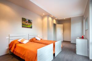 2 camas con sábanas de color naranja en una habitación en Como Lake Amazing View - byMyHomeinComo, en Moltrasio