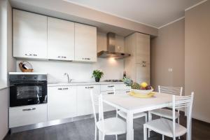 a kitchen with white cabinets and a white table and chairs at Como Lake Amazing View - byMyHomeinComo in Moltrasio