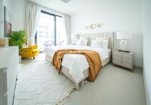 Gorgeous 1 Bed Apartment in Blue Bay Walk في الشارقة: غرفة نوم بيضاء بسرير كبير وكرسي اصفر +33 صورة