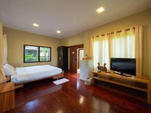 une chambre avec un grand lit et une télévision à écran plat dans l'établissement The Frog Khao Yai Resort, à Ban Tha Chang
