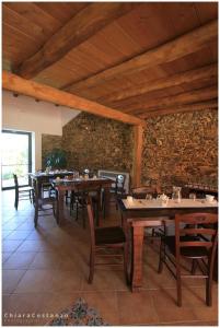 a dining room with tables and chairs and a stone wall at Antico Casale in Gioiosa Marea