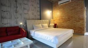a bedroom with a white bed and a red couch at One Beat Vintage&Bistro in Ban Puk (1)