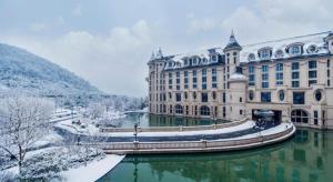 un grand bâtiment avec une rivière en face dans l'établissement Yin Run Jin Jiang Castle Hotel, à Huangshu