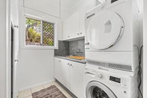 Un lavadero blanco con lavadora y secadora. en Peaceful Family Home: 4-Bed Pool Alfresco Dining, en Albany Creek