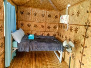 Kleines Zimmer mit einem Bett und einem Ventilator. in der Unterkunft Hilltop chalet, with AC, private bathroom, kitchen & balcony with views in Coron