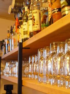 a bunch of glasses on a shelf with bottles at Alpking Hostel in Ellmau