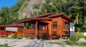 a large wooden cabin with a mountain in the background at Phuphayot Resort in Huai Yot