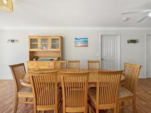 Un comedor con mesa y sillas de madera. en Spacious 4-Bed Home 2-Min to the Beach, en Broulee