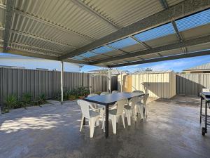 un patio con mesa y sillas bajo toldo en Spacious 4-Bed Home 2-Min to the Beach, en Broulee