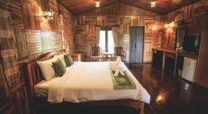 une chambre avec un lit dans une pièce aux murs en bois dans l'établissement Baan Baitan Resort, à Ban Tha Fat 172 autres photos