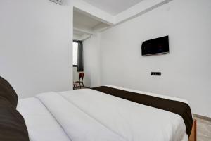 Un dormitorio con una cama blanca y un televisor en la pared. en Collection O Kanifnath Trek Pune, en Jadhavwadi