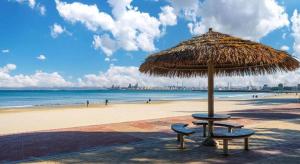a beach with two chairs and a straw umbrella at Pohang Hotel View in Pohang