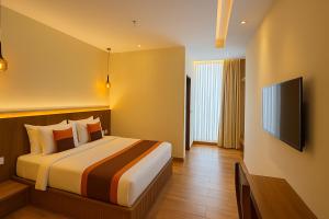 um quarto de hotel com uma cama e uma TV de tela plana em The Miste Munnar By D2V em Munnar