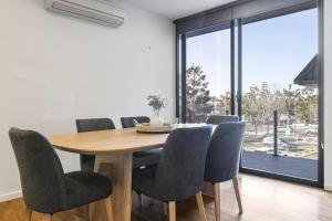 Un comedor con mesa y sillas de madera. en Oceanfront 2-Bed With Balcony & Study Nook, en Geelong