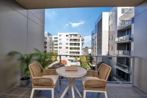 a patio with a table and chairs on a balcony at Modern 1-Bed Unit with Pool Views and Balcony in Canberra