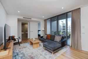 a living room with a couch and a tv at Modern 1-Bed Unit with Pool Views and Balcony in Canberra