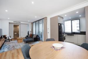 a living room with a dining room table and a kitchen at Modern 1-Bed Unit with Pool Views and Balcony in Canberra +8 photos