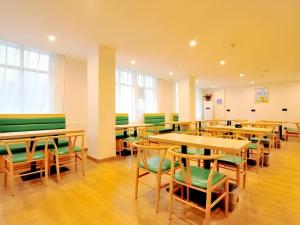 a classroom with wooden tables and green chairs at GreenTree Inn Haikou City Wuzhishan Road in Haikou