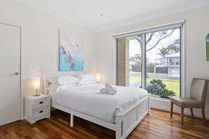 Una habitación blanca con una cama y una ventana en Seaside 3-Bed Home Direct Beach Access, en Safety Beach