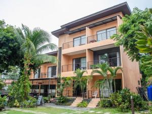 un bâtiment avec des palmiers devant dans l'établissement OYO 567 U Residence, à Ban Lamai