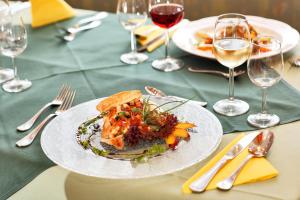 einen Teller mit Essen auf einem Tisch mit Gläsern Wein in der Unterkunft Pension Waldwinkel in Lenzkirch
