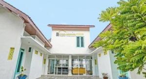 une maison blanche avec des arbres devant dans l'établissement OYO Life 91323 Omah Victoria Homestay & Culinary, à Tempuran