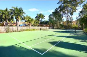 a tennis court with palm trees in the background at Harbour Town Cozy Suite in Gold Coast