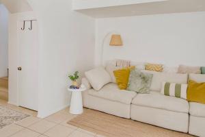 a white couch with colorful pillows in a living room at Harbour Town Cozy Suite in Gold Coast +3 photos