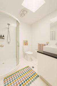 a white bathroom with a shower and a sink at Harbour Town Cozy Suite in Gold Coast