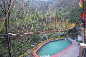 un puente colgante sobre una poza en las montañas en Kempty Lake Waterfall Resort - Run by Anaysha Group, en Mussoorie