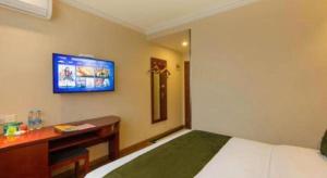 ein Schlafzimmer mit einem Bett und einem Fernseher an der Wand in der Unterkunft GreenTree Inn Suzhou Guanqian Street Leqiao Metro Station in Suzhou