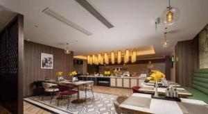 eine Küche und ein Wohnzimmer mit Tischen und Stühlen in der Unterkunft Jinjiang Metropolo Hotel - Taizhou Wanda Plaza in Taizhou