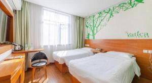 ein Hotelzimmer mit zwei Betten und einem Schreibtisch in der Unterkunft Vatica JiangSu WuXi Xihu Middle Road Jinhai Park Hotel in Wuxi