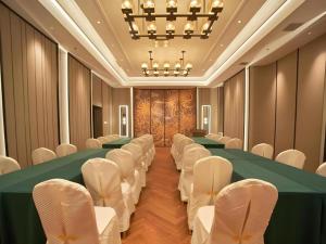 einen Konferenzraum mit einem langen Tisch und weißen Stühlen in der Unterkunft Metropolo Hotel Shijiazhuang Yuhua Wanda Plaza in Shijiazhuang