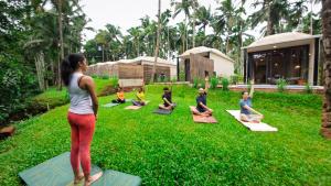 Hipnoetic Goa - Luxury Private Pool Cottages في Quepem: مجموعة من الناس يقومون باليوغا في العشب +7 صور