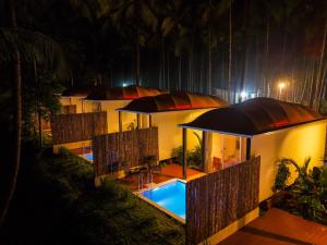 Hipnoetic Goa - Luxury Private Pool Cottages في Quepem: منزل به حمام سباحة في الليل