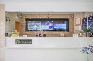 une femme se tenant derrière un comptoir dans un magasin dans l'établissement Vatica Beijing Miyun West Guoyuan Street Hotel, à Xiaotangzhuang