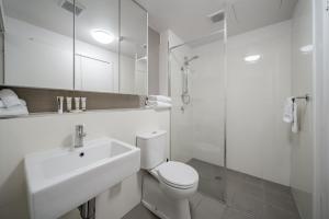 Un baño blanco con lavabo e inodoro. en Lakeside 1-Bed with AC, Parking & Balcony, en Tuggeranong